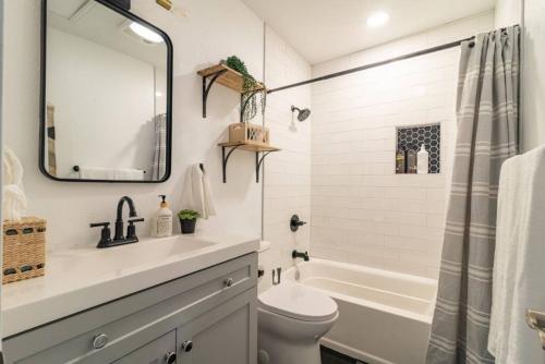 a bathroom with a sink and a toilet and a tub at Downtown Lonestar Bungalow at Beer Ranch Project in Wimberley