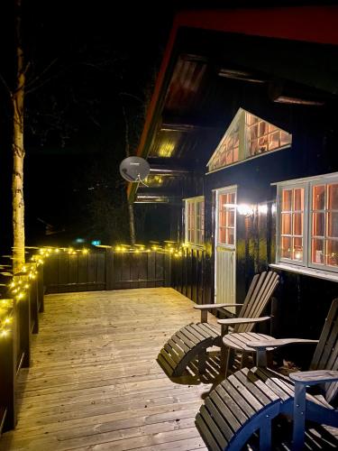 a wooden deck with chairs and lights at night at Three bedroom holiday house with jacuzzi in Bjorli , pets allowed in Bjorli