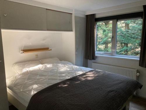 1 dormitorio con cama y ventana en Luxe chalet met airco bij bos en zwemwater en Hoevelaken