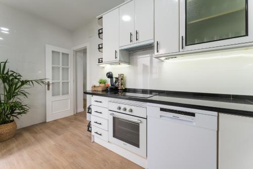 a kitchen with white cabinets and a black counter top at Casa Augusto - junto al Teatro Romano, con garaje in Merida