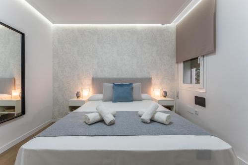 a white bedroom with a large bed with two pillows at Casa Augusto - junto al Teatro Romano, con garaje in Merida