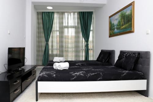 a bedroom with a black bed and a television at Hotel Xhema in Pristina