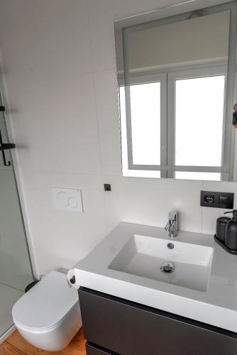 a white bathroom with a toilet and a sink at Vakantiehuis Joanitas in Bredene