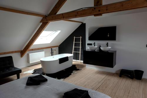 a attic room with a bath tub and a television at Vakantiehuis Joanitas in Bredene