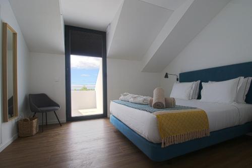 a bedroom with a large bed and a large window at Pêro Teive Bay Apartments Hotel in Ponta Delgada