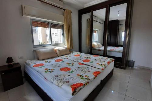 1 dormitorio con 1 cama grande con manta de flores en Two bedroom furnished apartment in Amman near Boulevard Abdali. en Amán