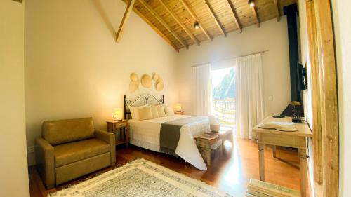 a bedroom with a bed and a chair and a window at Pousada Altoé da Montanha in Venda Nova do Imigrante