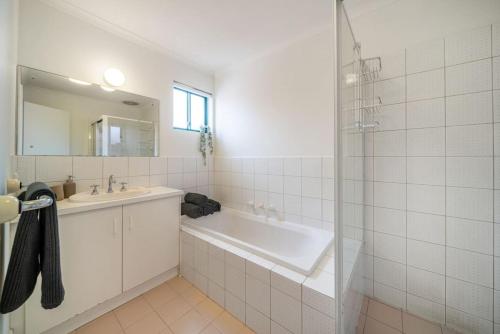 uma casa de banho com uma banheira, um lavatório e um espelho. em Poppy on the Lane - WiFi CBD em Thebarton