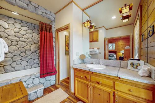 baño con lavabo y pared de piedra en Branchwater Lodge, en Big Bear Lake