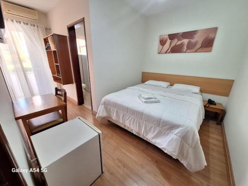 a bedroom with a white bed and a wooden floor at Hotel Itapema in Valinhos