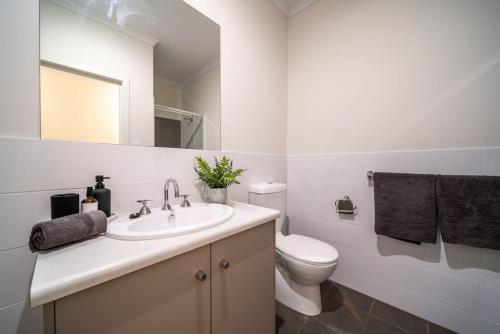 a bathroom with a sink and a toilet and a mirror at Black Oak at Brompton in Bowden