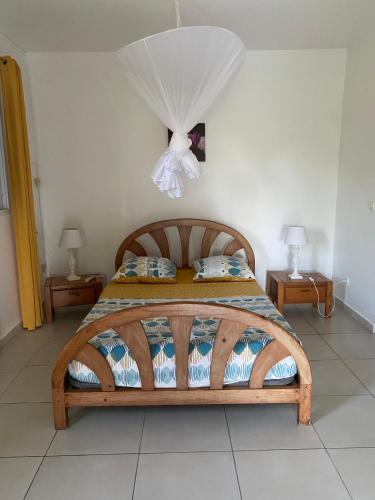 1 dormitorio con 1 cama de madera y 2 mesas en Au Gré des Alizés - Kaz Soley Péyi, en Capesterre