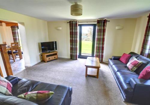 a living room with a couch and a tv at Y Beudy in Llandinam