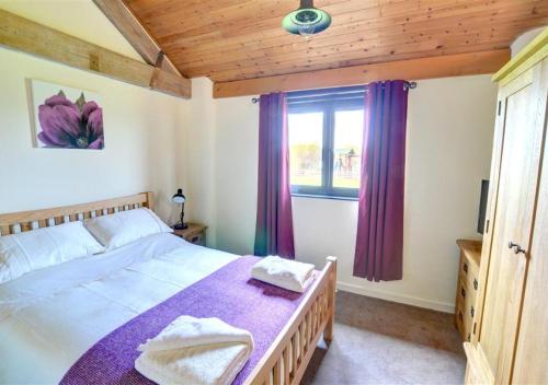 a bedroom with a bed and a window with purple curtains at Y Beudy in Llandinam