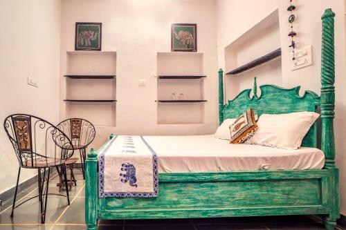 a bedroom with a green bed and two chairs at Soham Haveli Udaipur in Udaipur