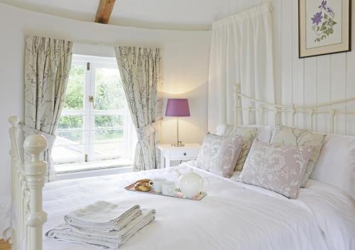 a white bed with a tray with a stuffed animal on it at Sampson's Mill in Wickham Market