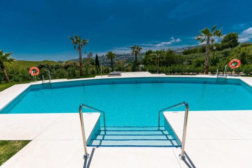 a large swimming pool with blue water and palm trees at Luxury La Cala Golf Retreat with terrace & pool in La Cala de Mijas