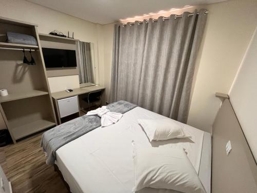 - une chambre avec un lit blanc et une fenêtre dans l'établissement Hotel Gold Ville, à Siqueira Campos