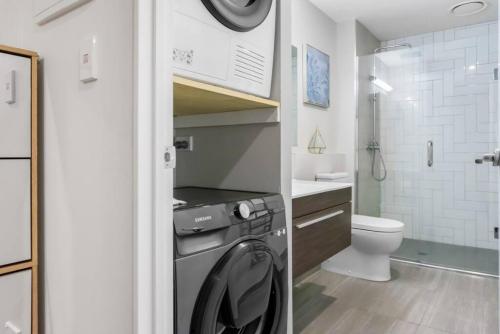a bathroom with a washing machine and a toilet at Quality in Heart of Albany - Wi-Fi - Free Parking in Auckland