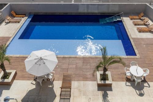 una piscina con 2 mesas y una sombrilla en Temporada do seu jeito - Apes na Enseada, en Guarujá