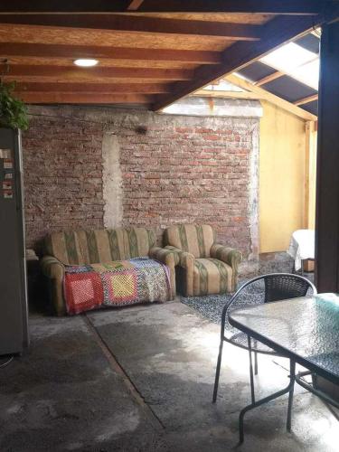 a room with two couches and a table and a brick wall at Casa 2 Habitaciones in Villarrica