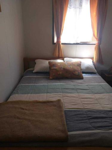 a bed with two pillows and a window in a bedroom at Casa 2 Habitaciones in Villarrica