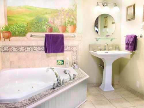 a bathroom with a tub and a sink and a painting at EJ Bowman House Bed & Breakfast in Lancaster