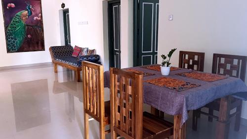 een eetkamer met een tafel en stoelen en een schilderij bij Aryavilla Heritage in Varkala