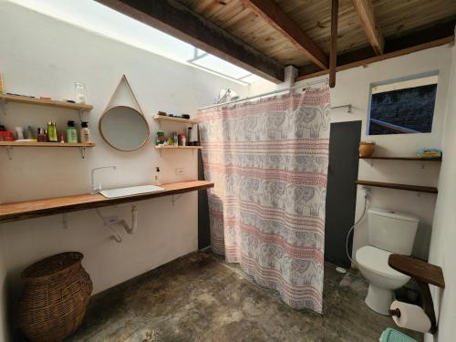 a bathroom with a shower curtain and a toilet at Loft romântico pé na areia in Itapoa
