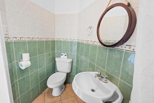 a bathroom with a toilet and a sink and a mirror at H4 LAS CABAÑAS in Corozal