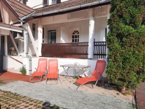 three chairs and a table in front of a house at Antal Apartmans Lunca de Sus Kulcsosház Gyimesfelsőlok in Lunca de Sus