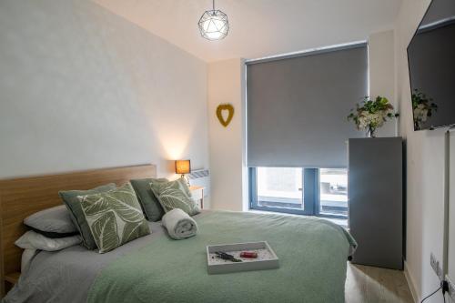 a bedroom with a green bed and a large window at Modern and Spacious Apartment in Salford Quays in Manchester