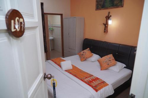 a small bedroom with a bed with orange pillows at Langkawi Country Lodge2 in Pantai Cenang