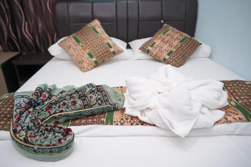 a bed with four pillows and a flower on it at Langkawi Country Lodge2 in Pantai Cenang