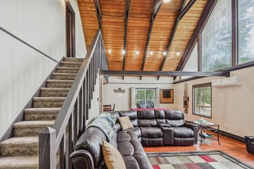 a living room with a leather couch and stairs at Poconos Chalet newly renovated, great location home in Tobyhanna