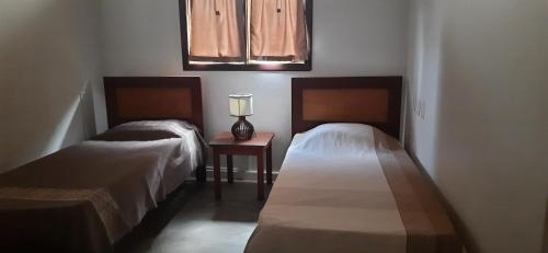 a bedroom with two beds and a table with a lamp at Casa Grande in Galinhos