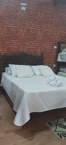 a bed in a room with a brick wall at Sitio Arco Iris da Lia in São Roque