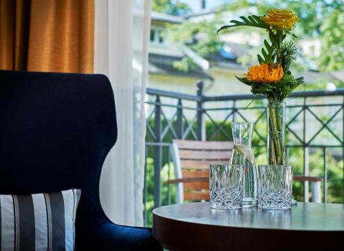 a table with glasses and a vase with flowers on it at Maison Messmer - ein Mitglied der Hommage Luxury Hotels Collection in Baden-Baden