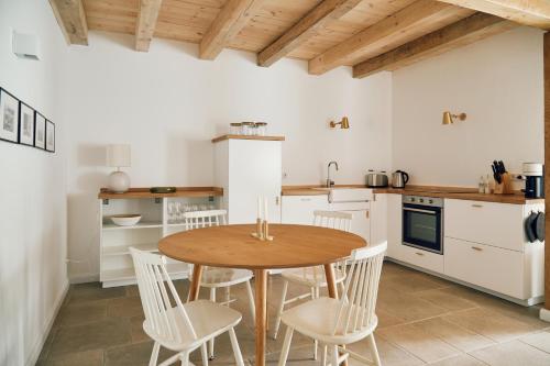 uma cozinha com uma mesa de madeira e cadeiras brancas em Schmiede em Barkelsby
