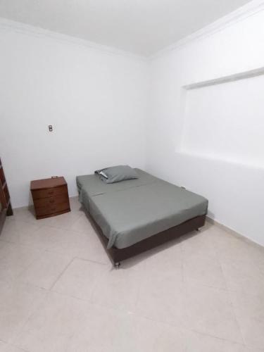 um quarto branco com uma cama e um armário de madeira em Casa hostalsol em Medellín