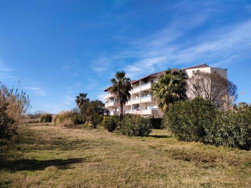 un edificio con palmeras frente a un campo en appartement en rez-de-chaussée et terrasse sans vis a vis, en Canet-en-Roussillon