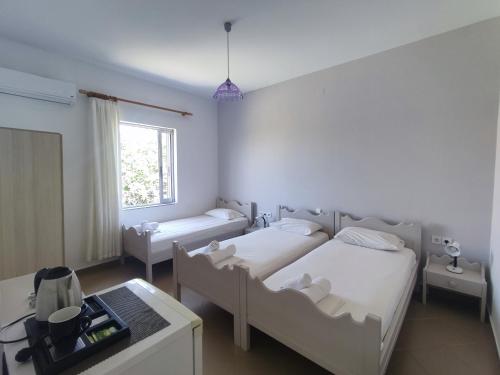 a bedroom with two beds and a table and a window at Maria Pantermou Rooms in Skala Eresou