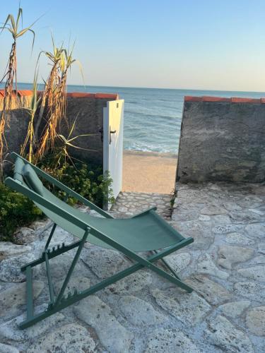 une chaise verte assise sur la plage près de l'océan dans l'établissement La perroche, à La Cotinière