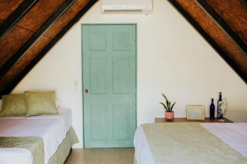 um quarto no sótão com 2 camas e uma porta azul em Los Olivos La Playa Hotel y Restaurante em Escuintla