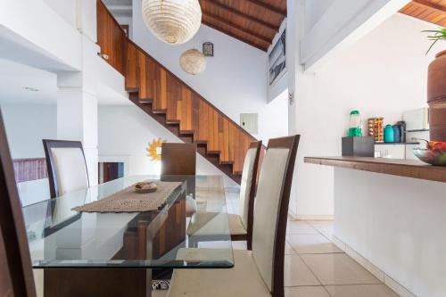 a dining room with a glass table and a staircase at Pousada Tehau Guest House in Búzios