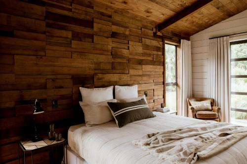a bedroom with a wooden wall with a bed at The Villa at Bali Garden Matakana in Omaha