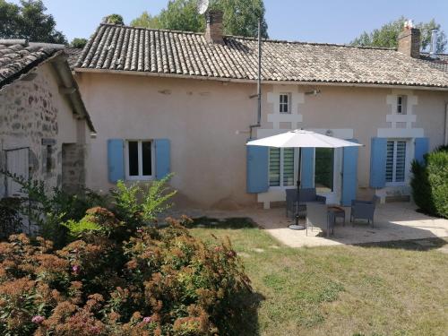 a house with an umbrella and a table and chairs at Gite La Passerelle de Giez - Vienne (86) Poitou-Charentes in Marigny-Chemereau