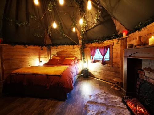 ein Schlafzimmer mit einem Bett in einem Blockhaus in der Unterkunft La cabane du Nuton Ardennais in Tournes