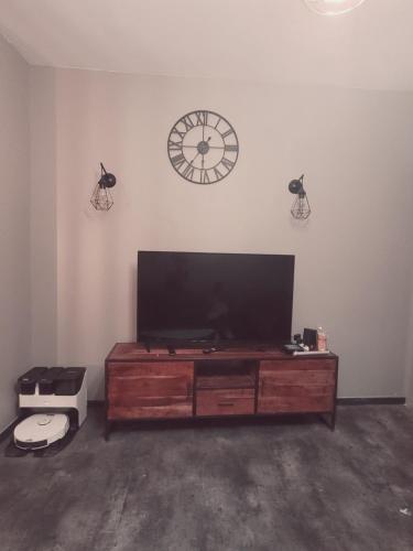 a living room with a television and a clock on the wall at Logement de Ville 4 chambres proche de Lille in Tourcoing