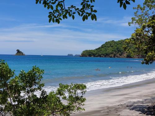 a beach with people swimming in the ocean at Santarena Hotel at Las Catalinas in Playa Flamingo